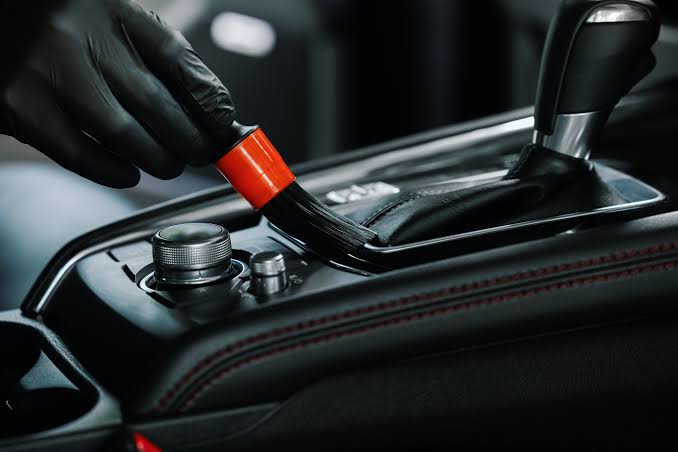 Detailing specialist carefully cleaning and protecting a vehicle's exterior surfaces